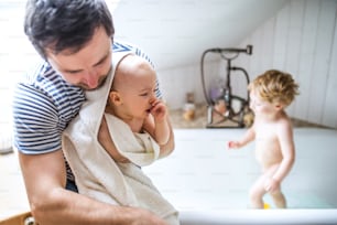 Père lavant deux enfants en bas âge dans la baignoire de la salle de bain à la maison. Congé de paternité.