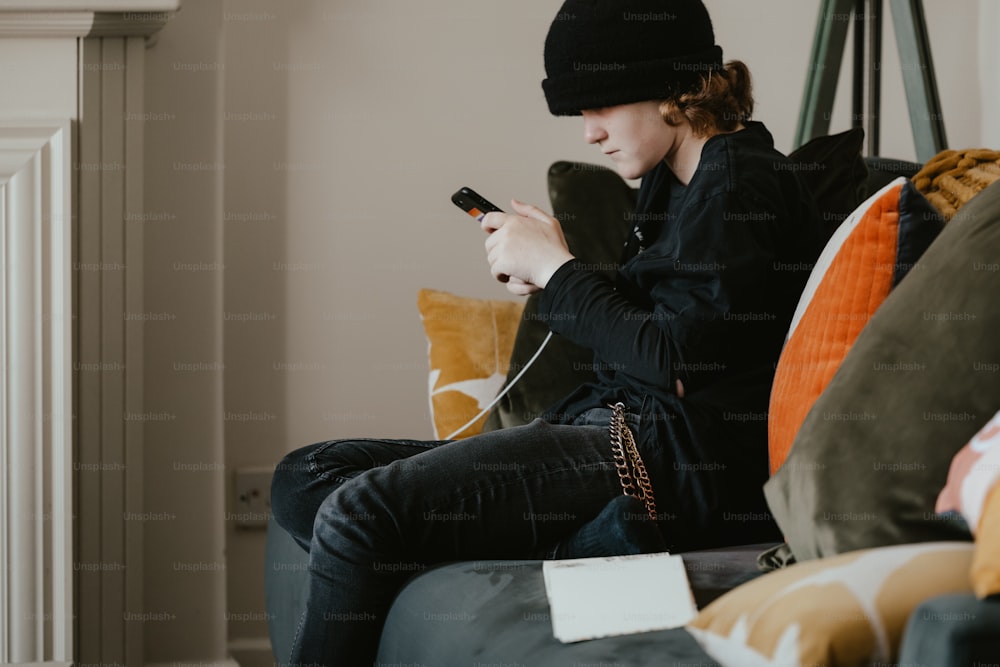 a woman sitting on a couch holding a cell phone