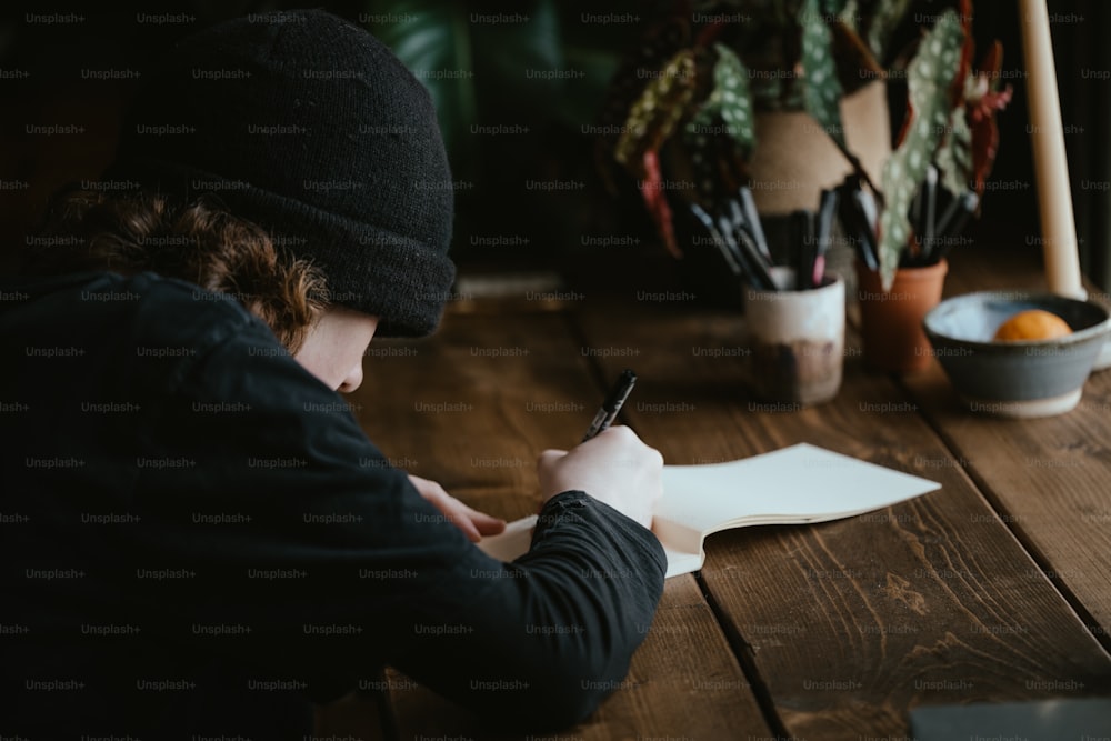 a person sitting at a table writing on a piece of paper