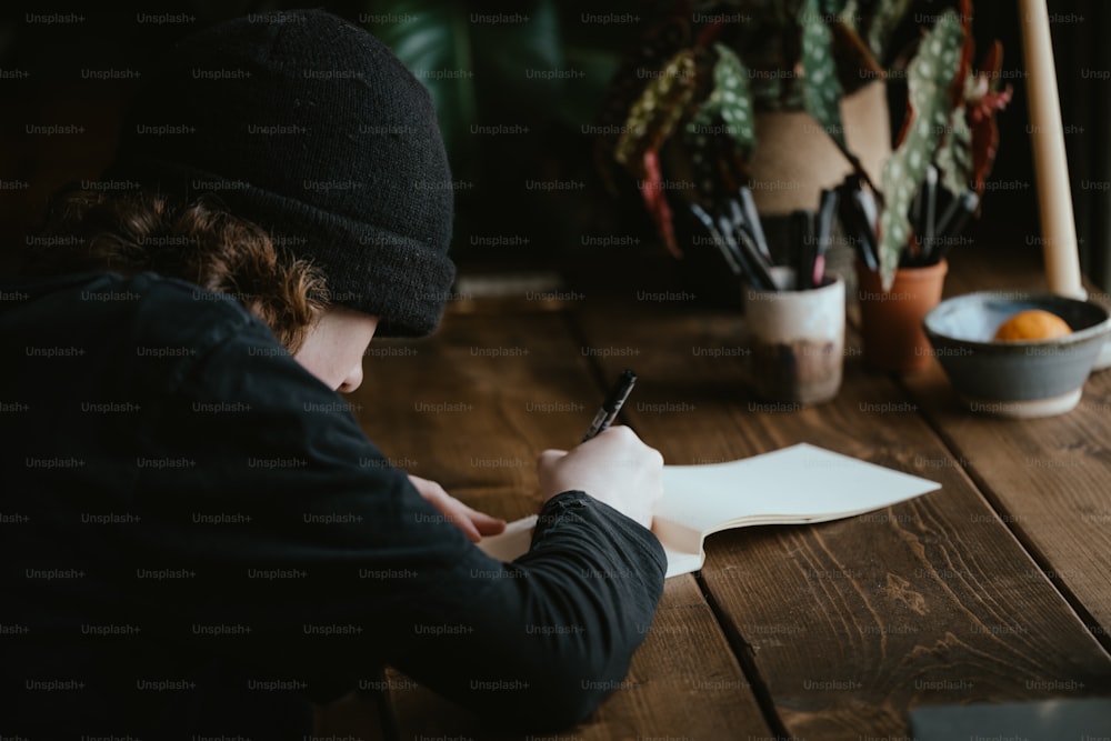 uma pessoa sentada em uma mesa escrevendo em um pedaço de papel
