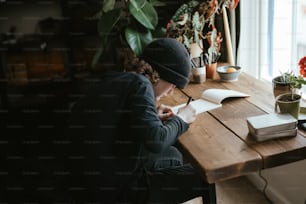 Una persona sentada en una mesa escribiendo en un libro