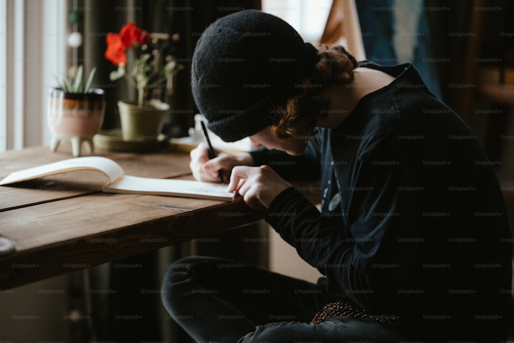 a person sitting at a table writing on a piece of paper