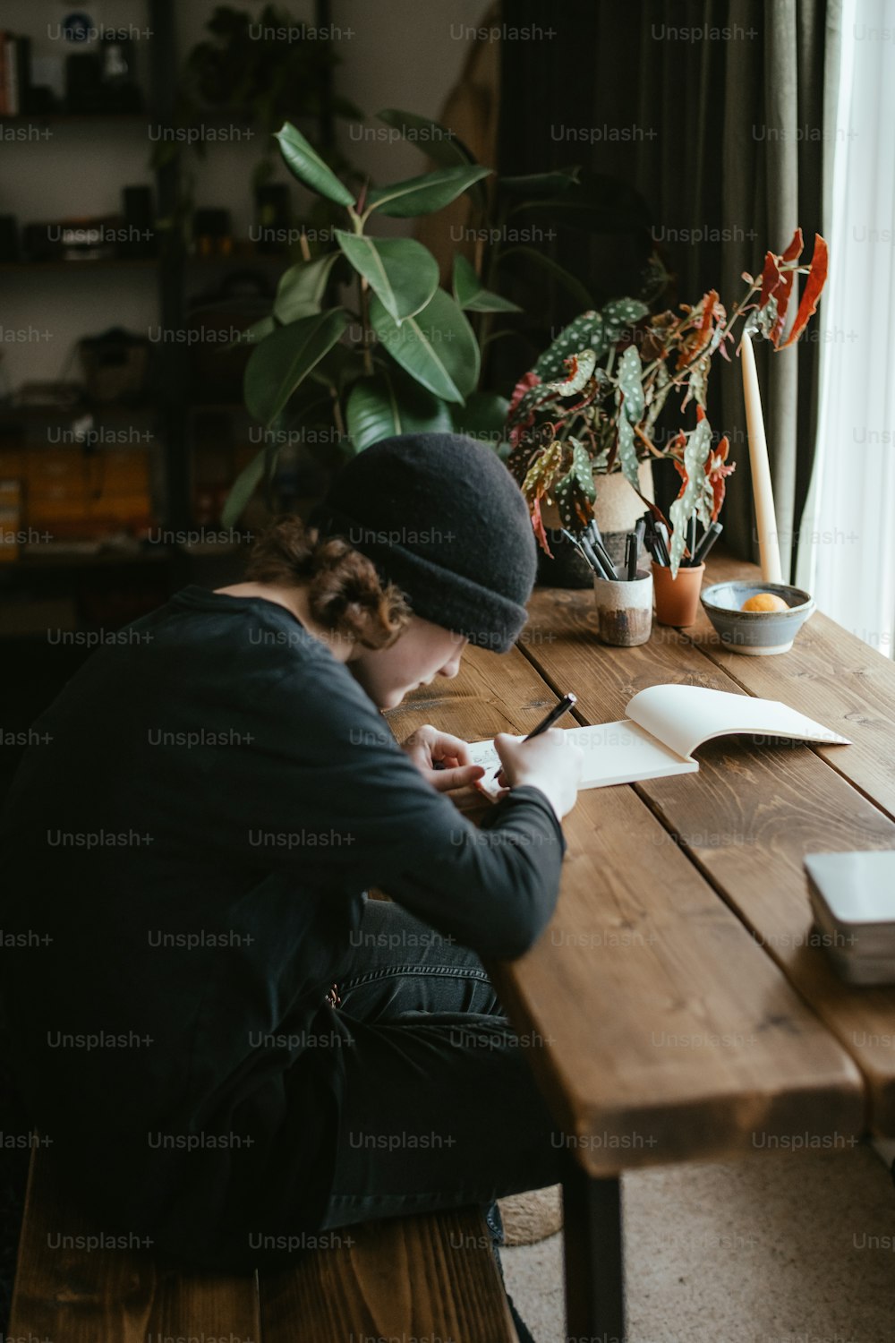 une personne assise à une table écrivant sur un morceau de papier