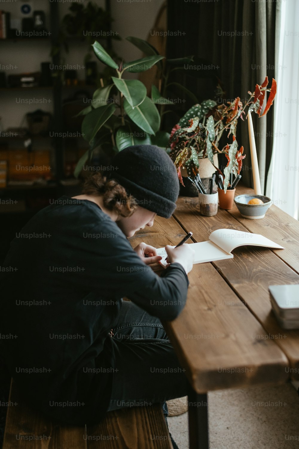 Una persona sentada en una mesa escribiendo en un pedazo de papel