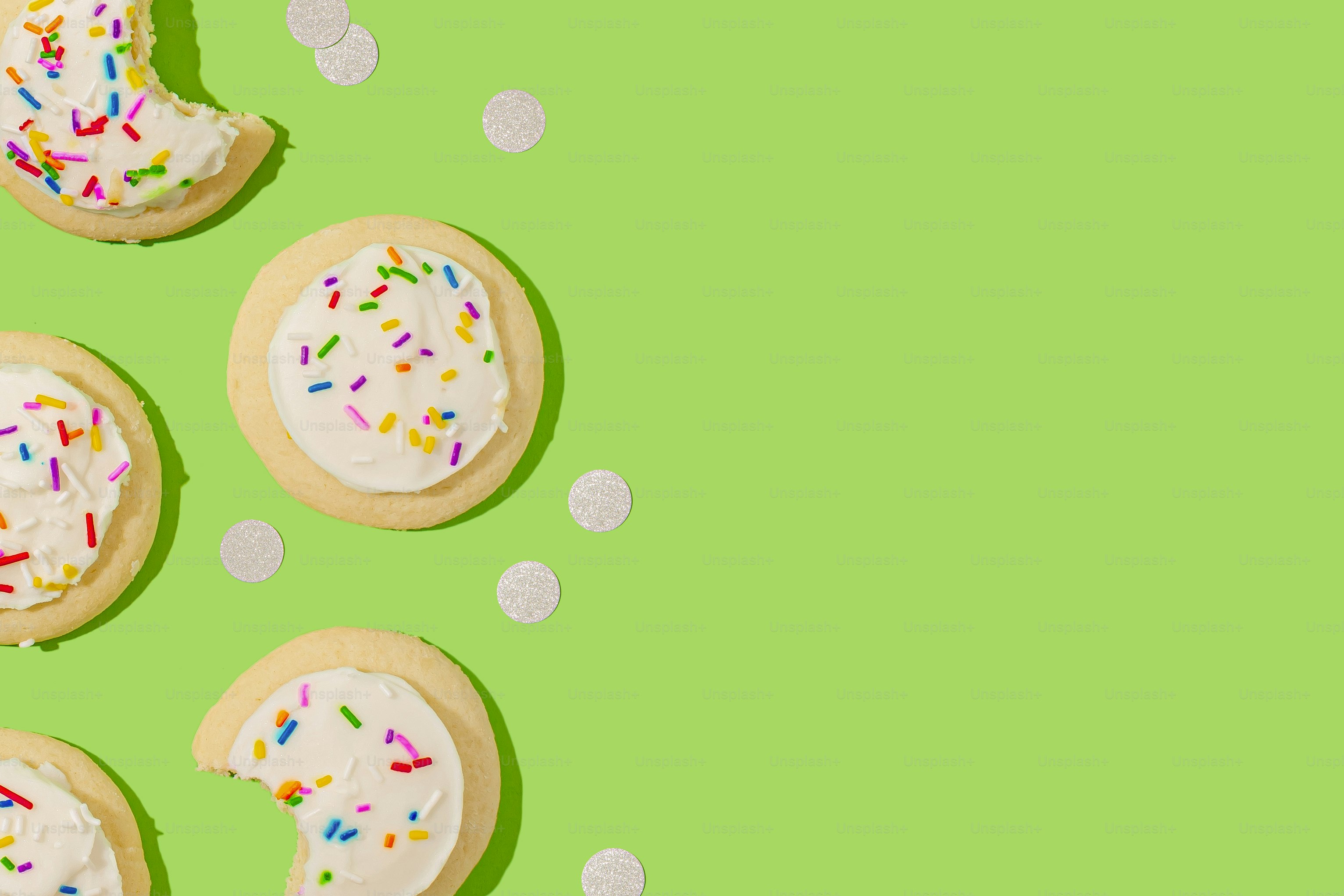 緑の背景に白いフロスティングと振りかけの3つのクッキー