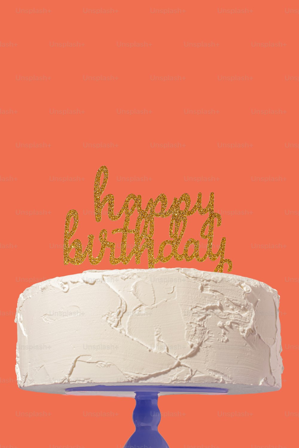 Un pastel blanco con un topper dorado de pastel de feliz cumpleaños