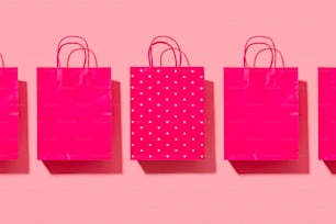 a row of pink shopping bags on a pink background