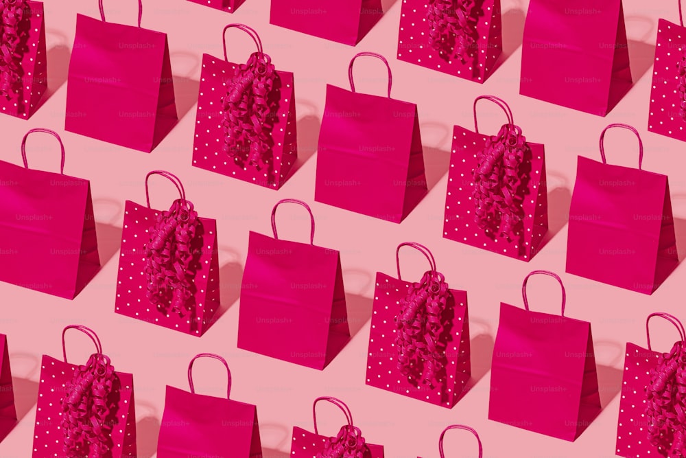 pink shopping bags are lined up against a pink background