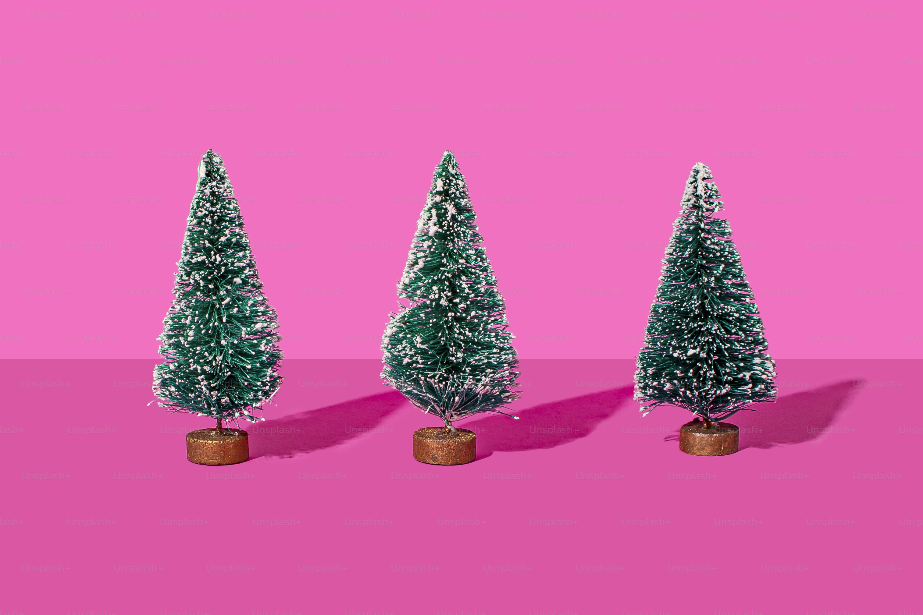three small christmas trees on a pink background