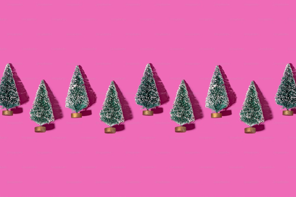 eine Reihe kleiner Weihnachtsbäume auf rosafarbenem Hintergrund