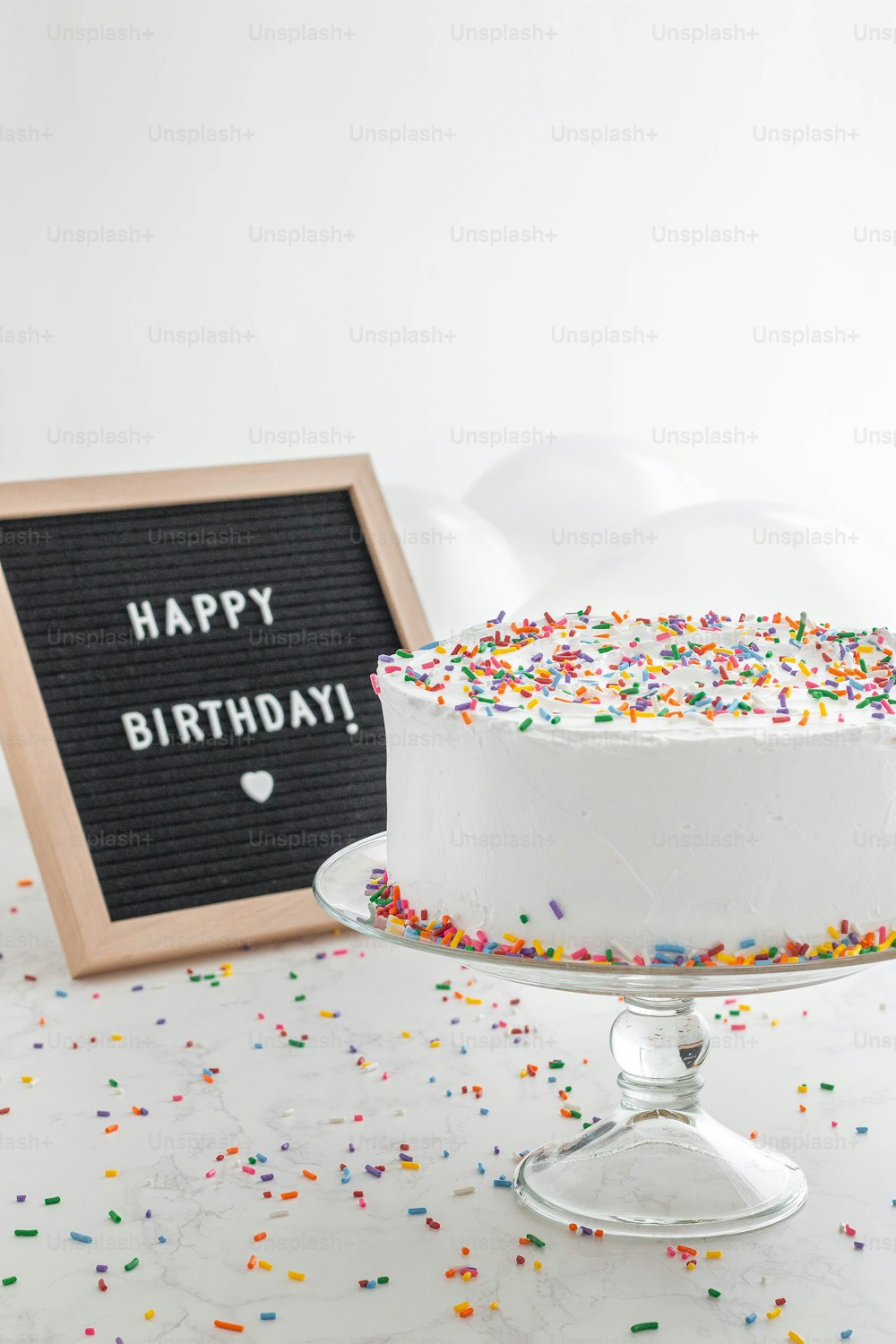 a birthday cake with sprinkles and a chalkboard sign