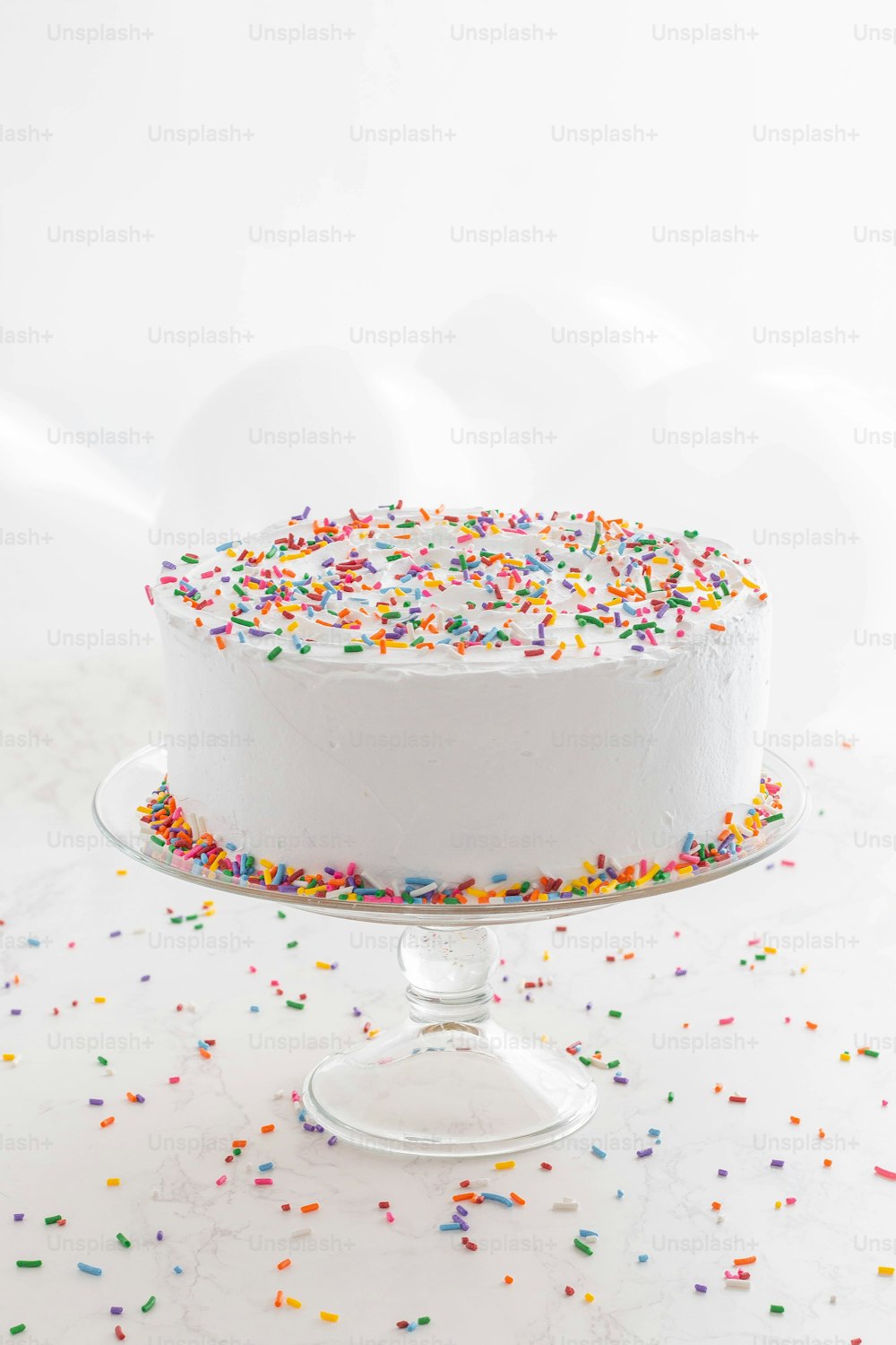 a white cake with sprinkles on a cake stand