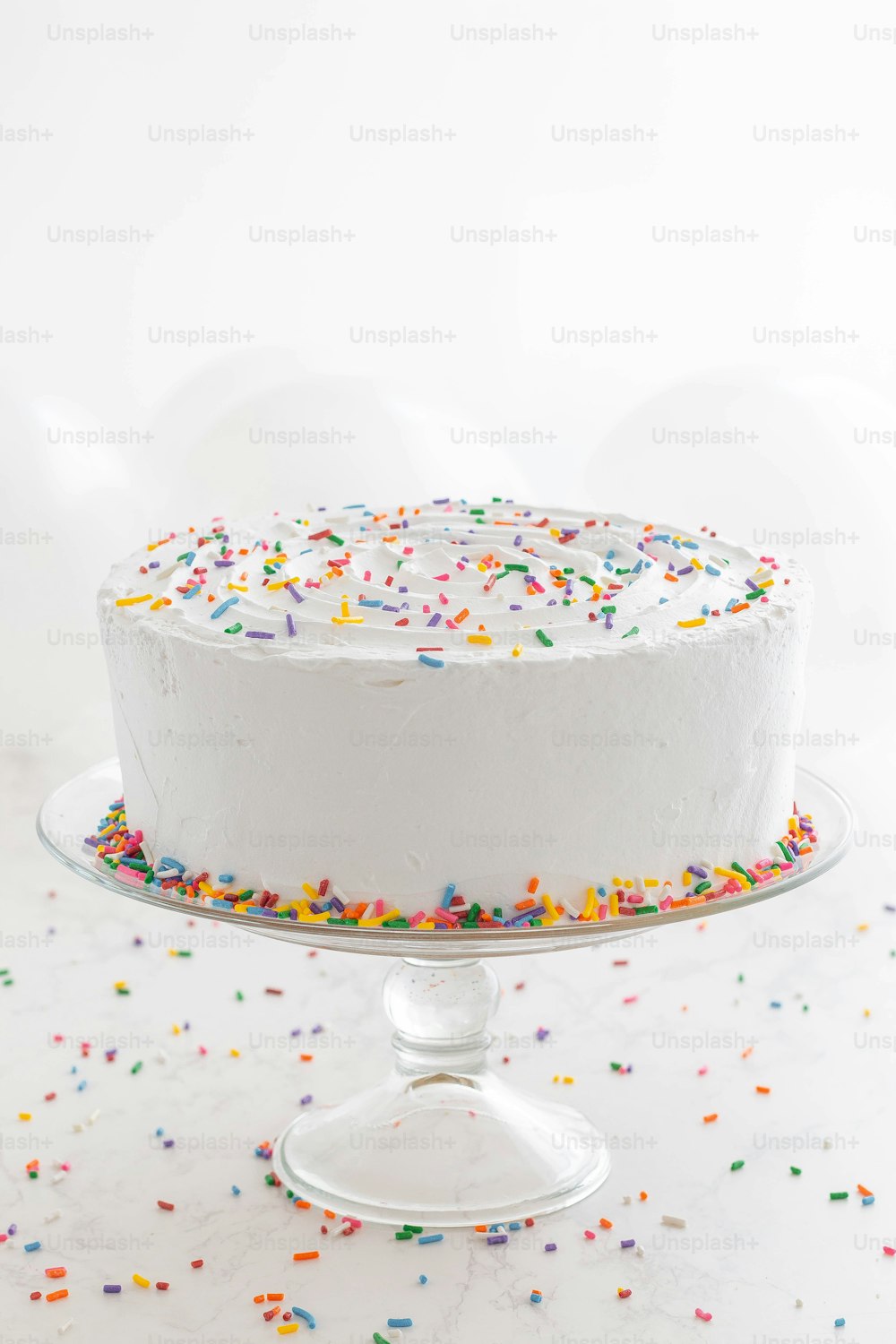 a white cake with sprinkles on a cake stand