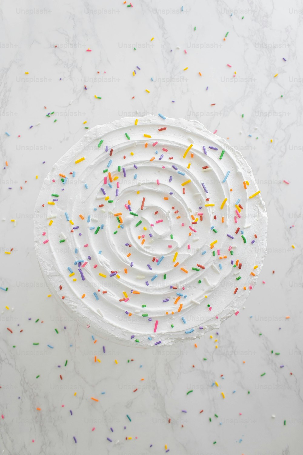 a spiral cake with sprinkles on a marble surface