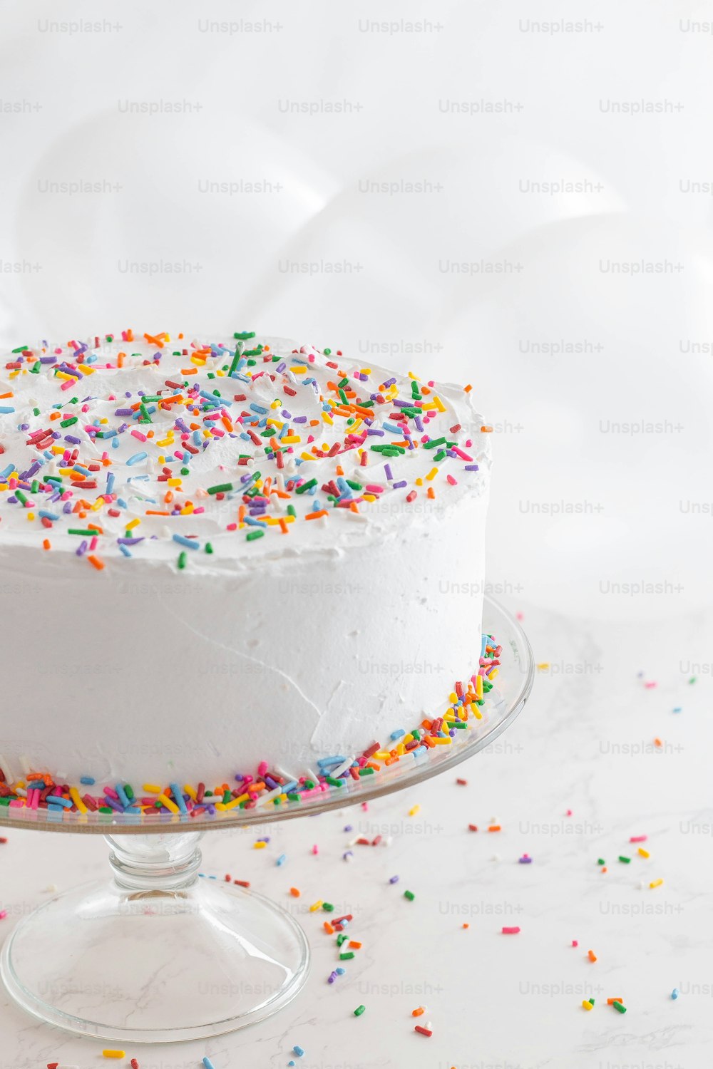 a white cake with sprinkles on a cake plate
