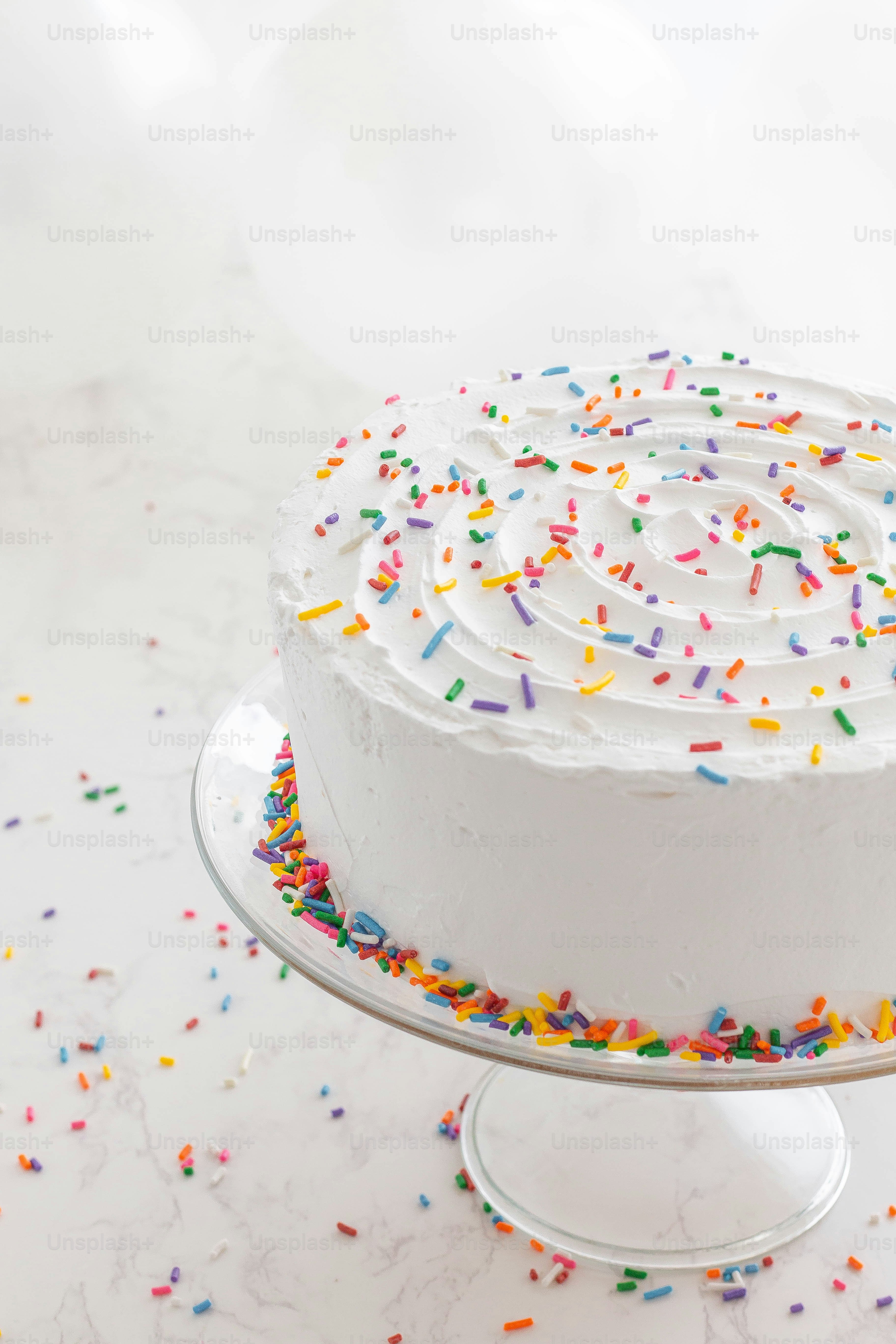 A cake with white frosting and sprinkles on a plate photo – Cake Image ...