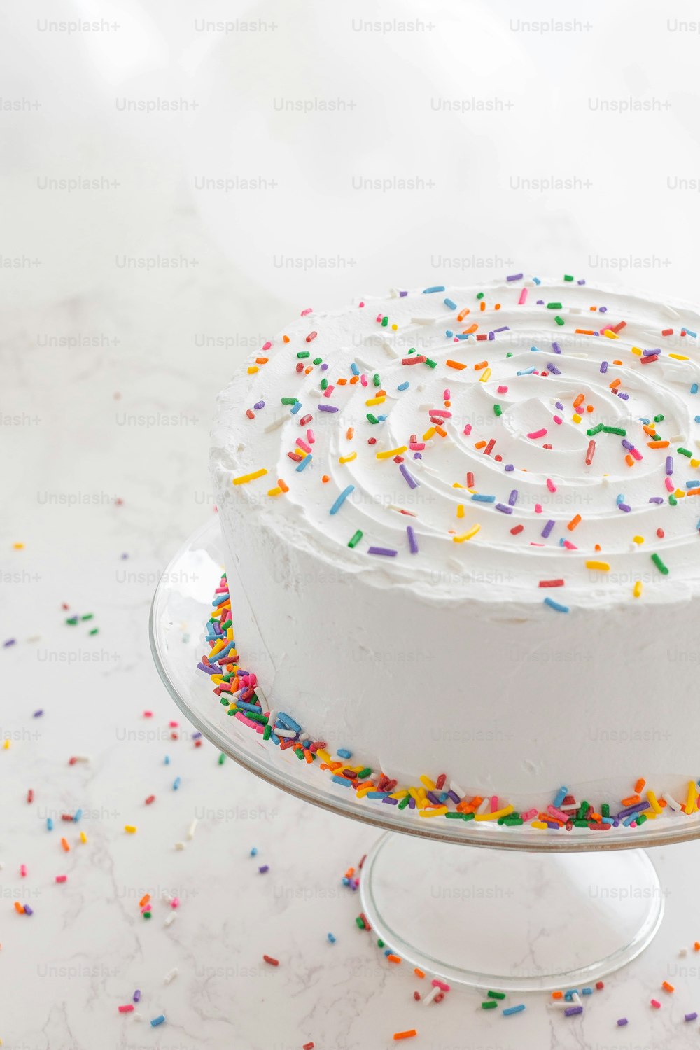 a cake with white frosting and sprinkles on a plate