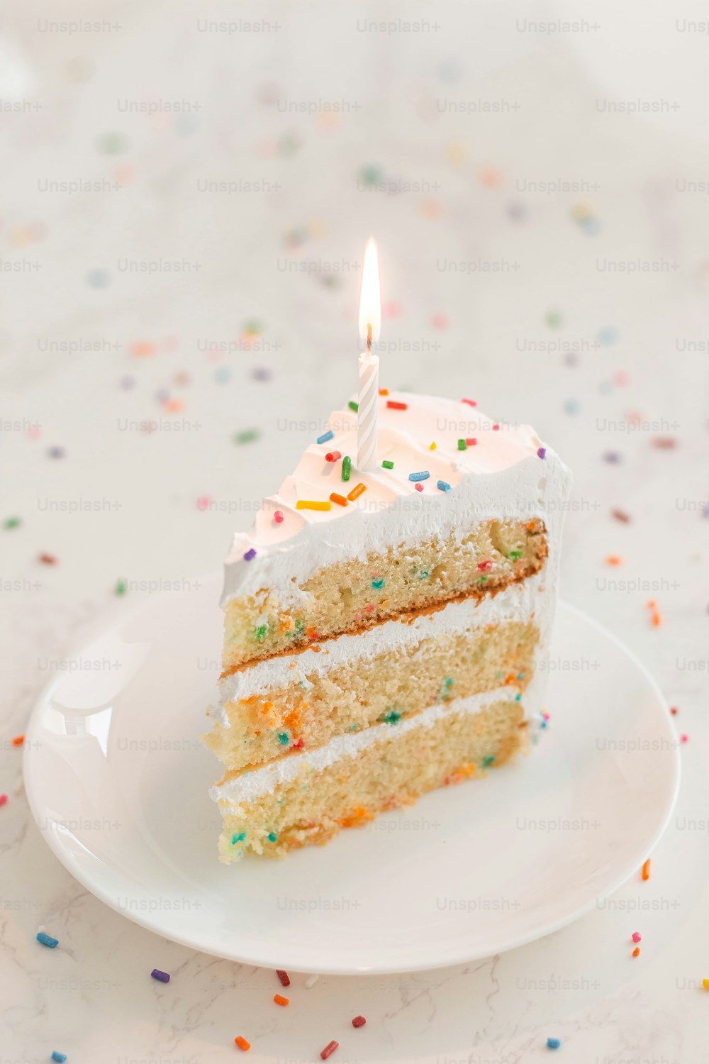 a slice of cake with a lit candle on a plate