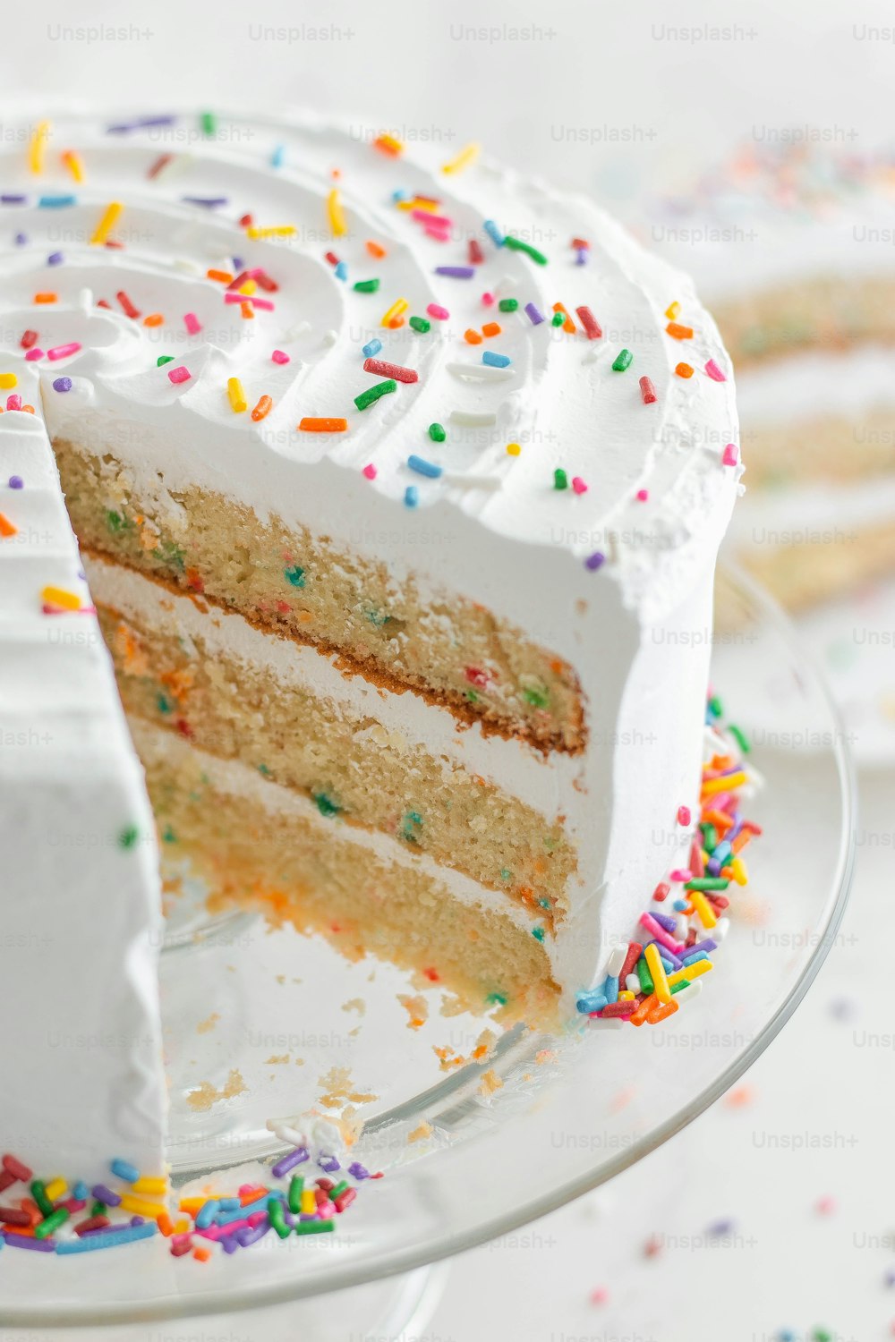 a slice of cake with white frosting and sprinkles