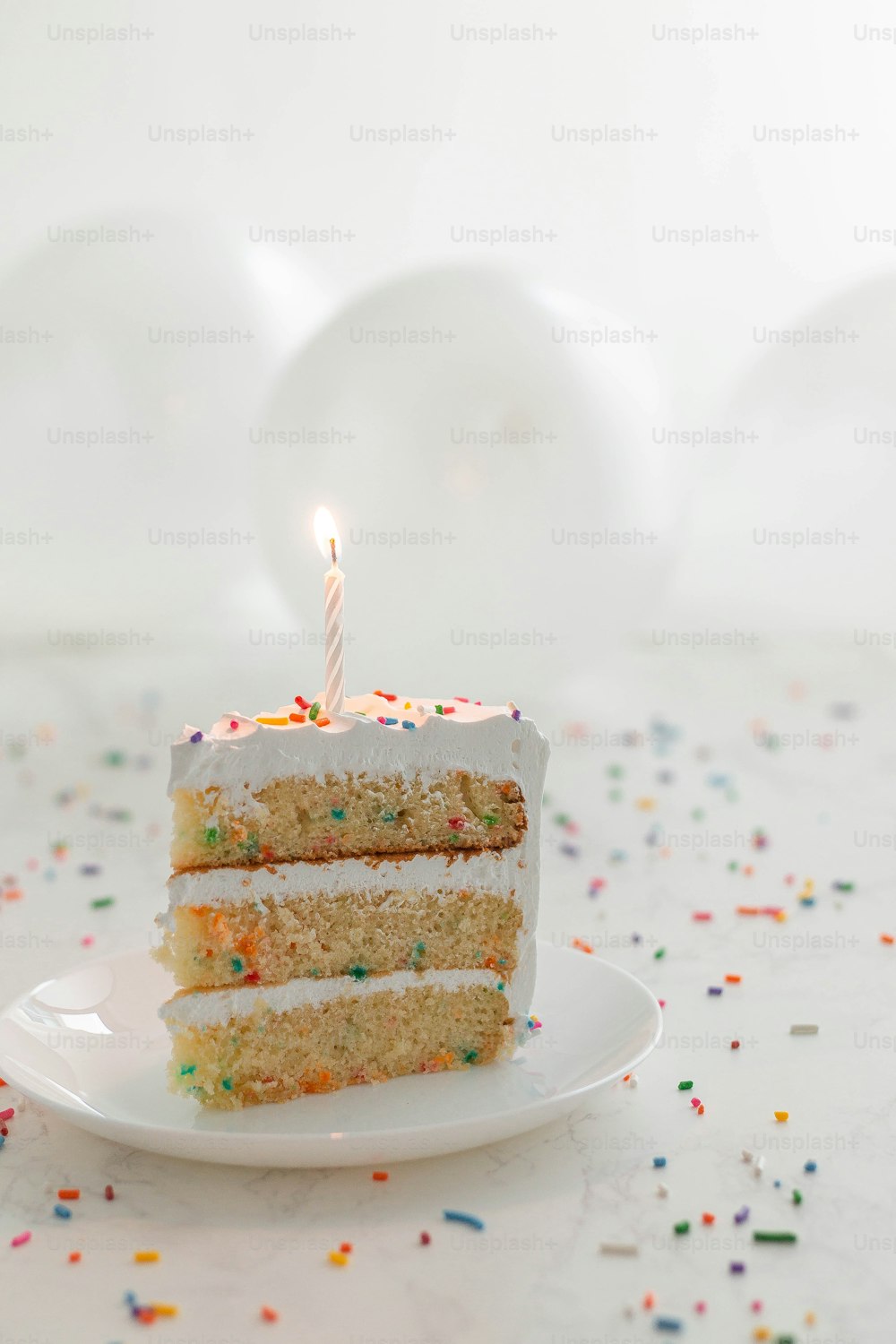 a slice of cake with a lit candle on a plate