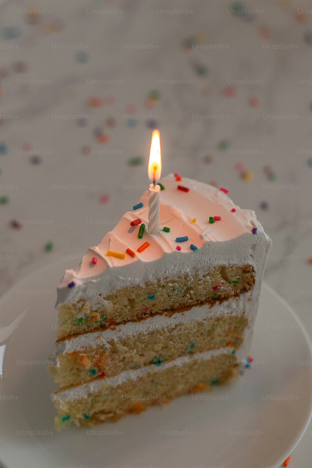 a slice of cake with a lit candle on it