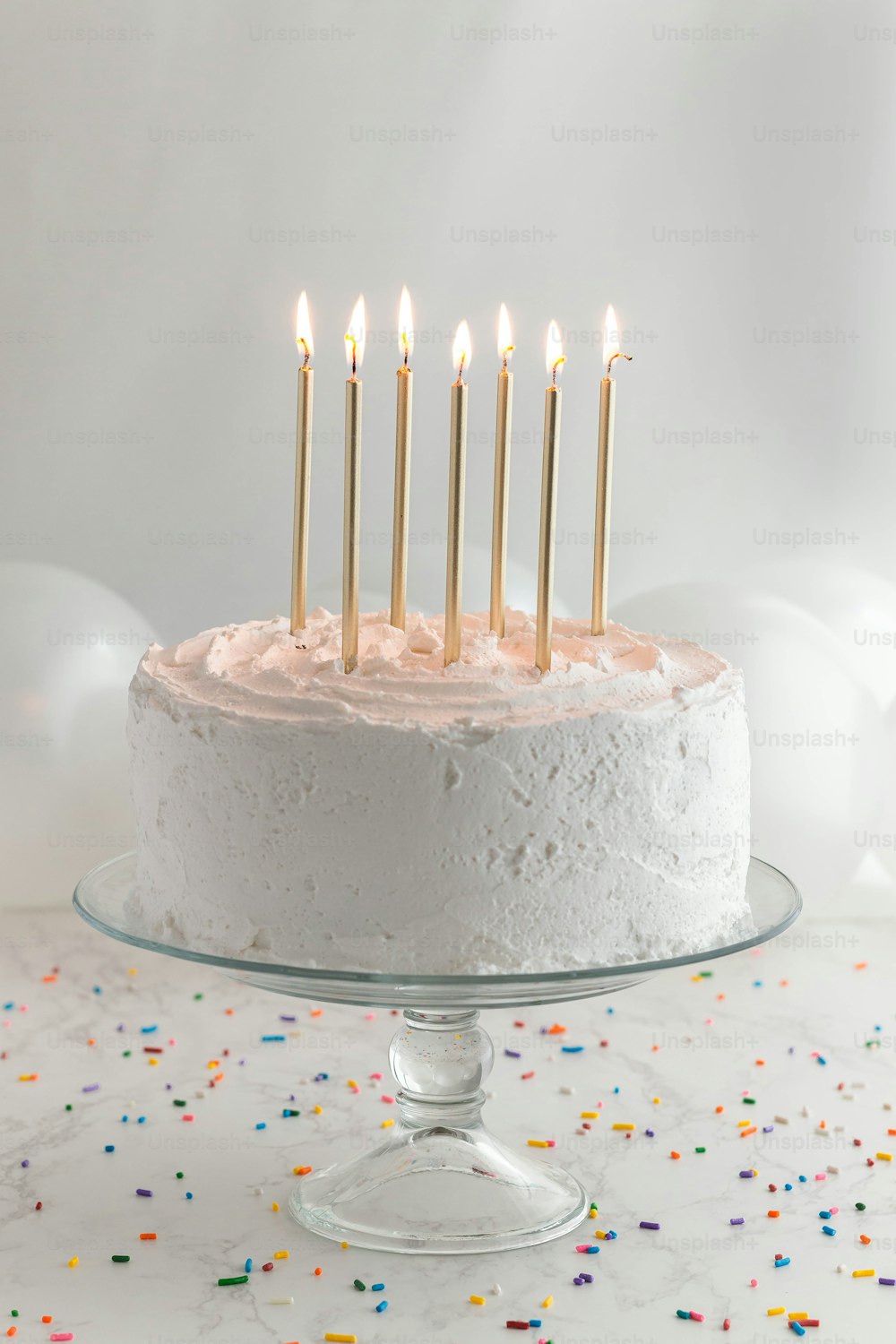 eine Geburtstagstorte mit weißem Zuckerguss und brennenden Kerzen