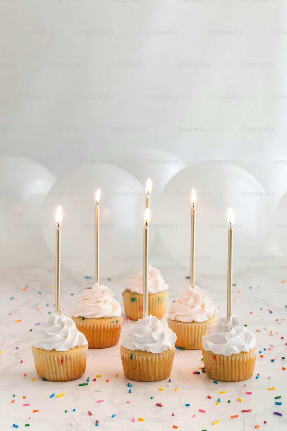 a group of cupcakes with white frosting and lit candles