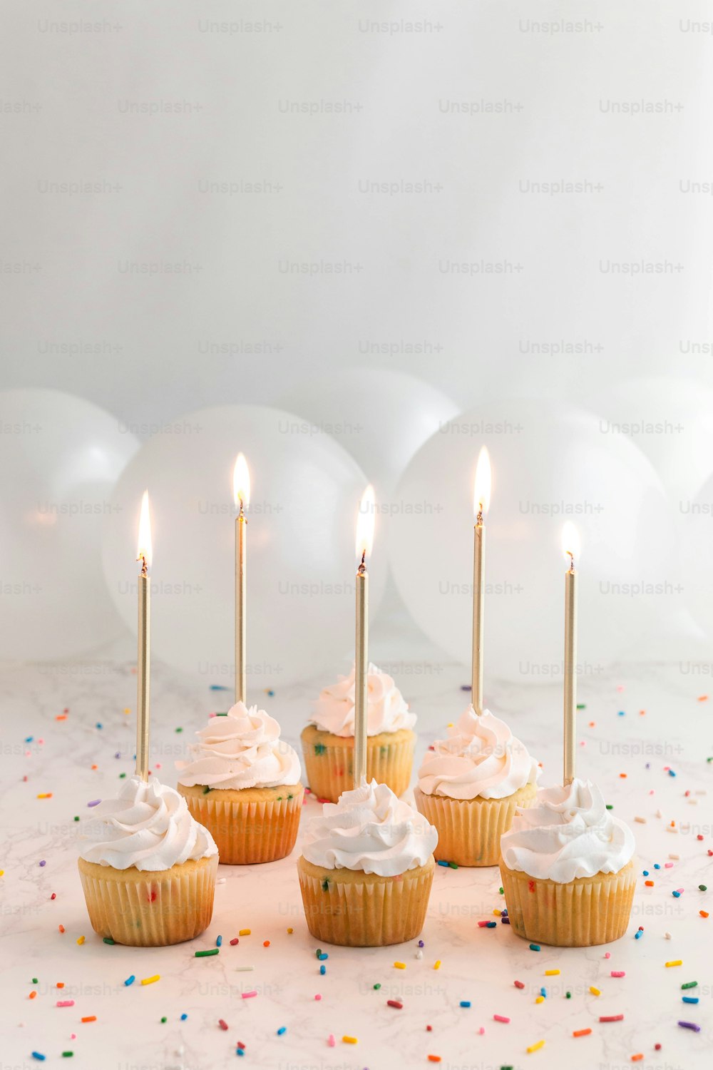 Un grupo de cupcakes con glaseado blanco y velas encendidas