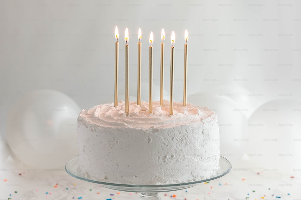 Un pastel de cumpleaños con glaseado blanco y velas encendidas