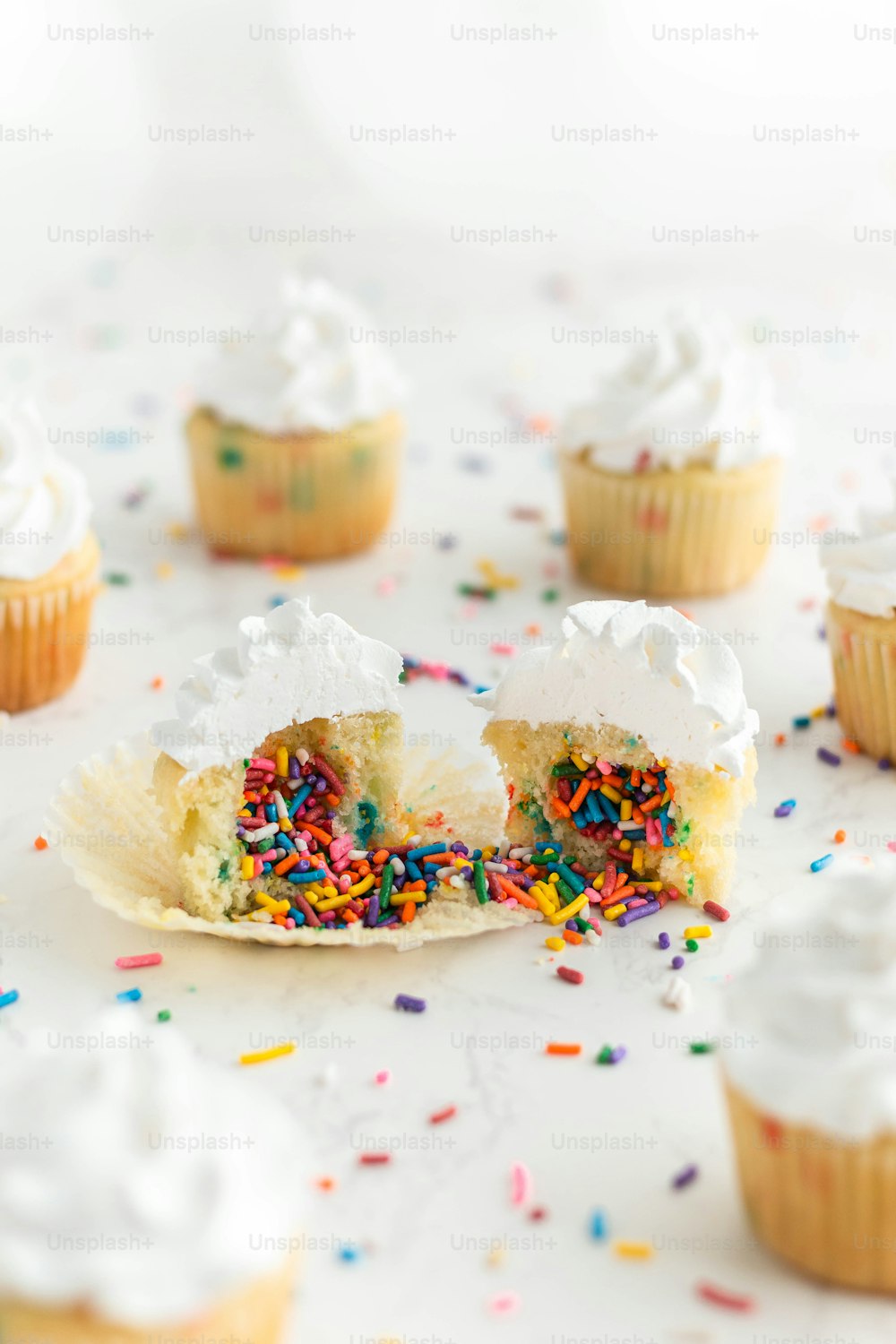 cupcakes with white frosting and sprinkles on a table