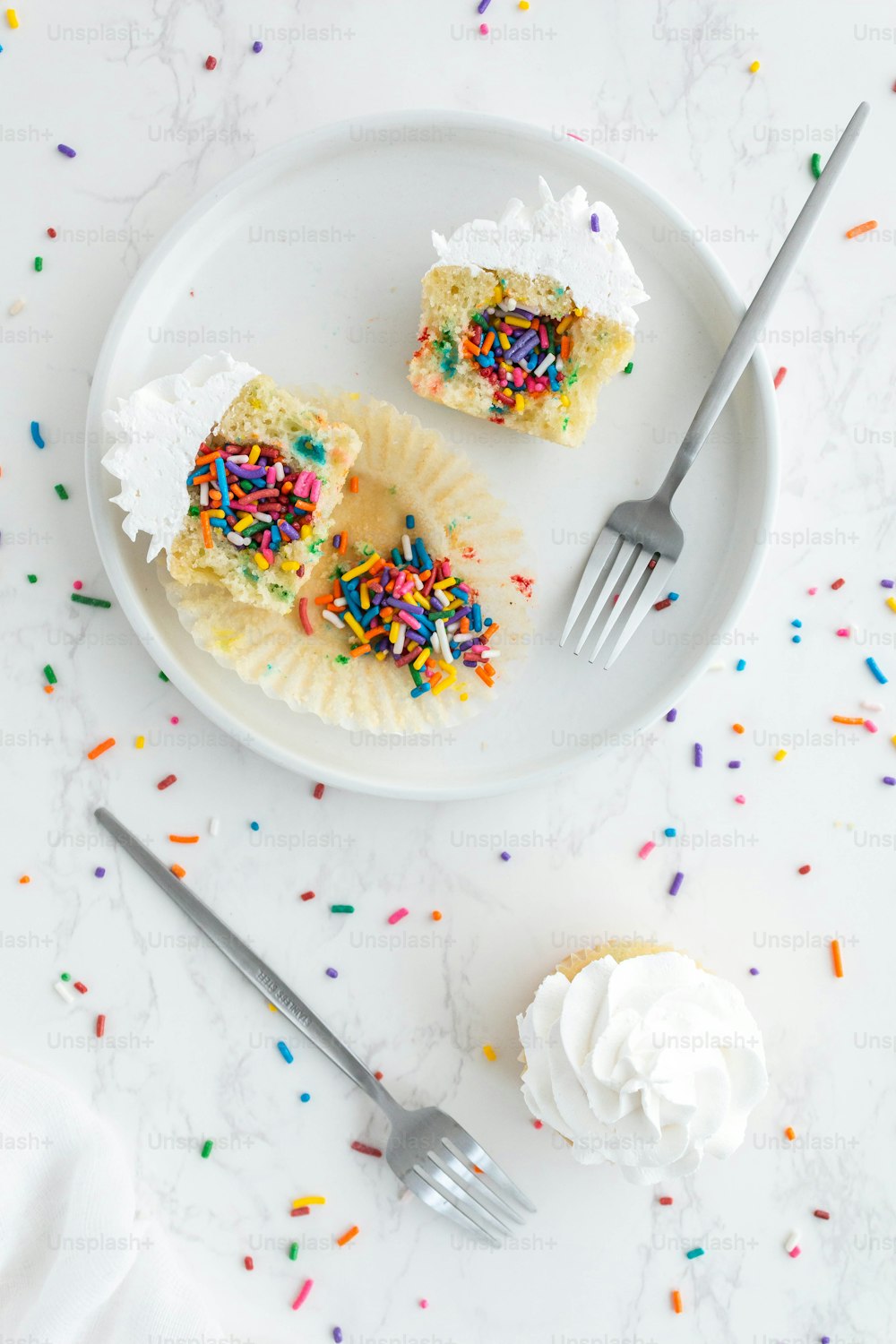 a white plate topped with two cupcakes covered in sprinkles