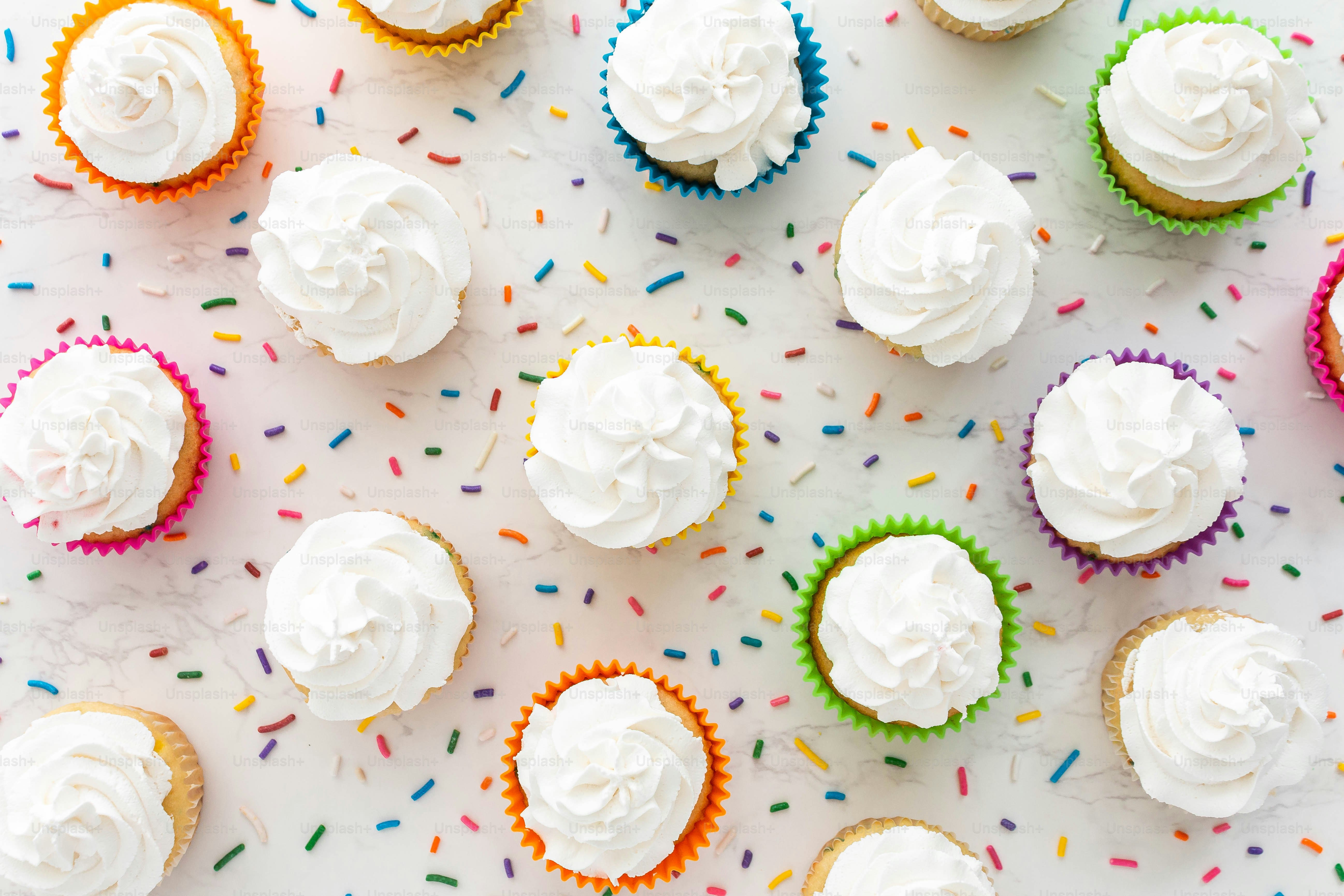 a bunch of cupcakes with white frosting and sprinkles