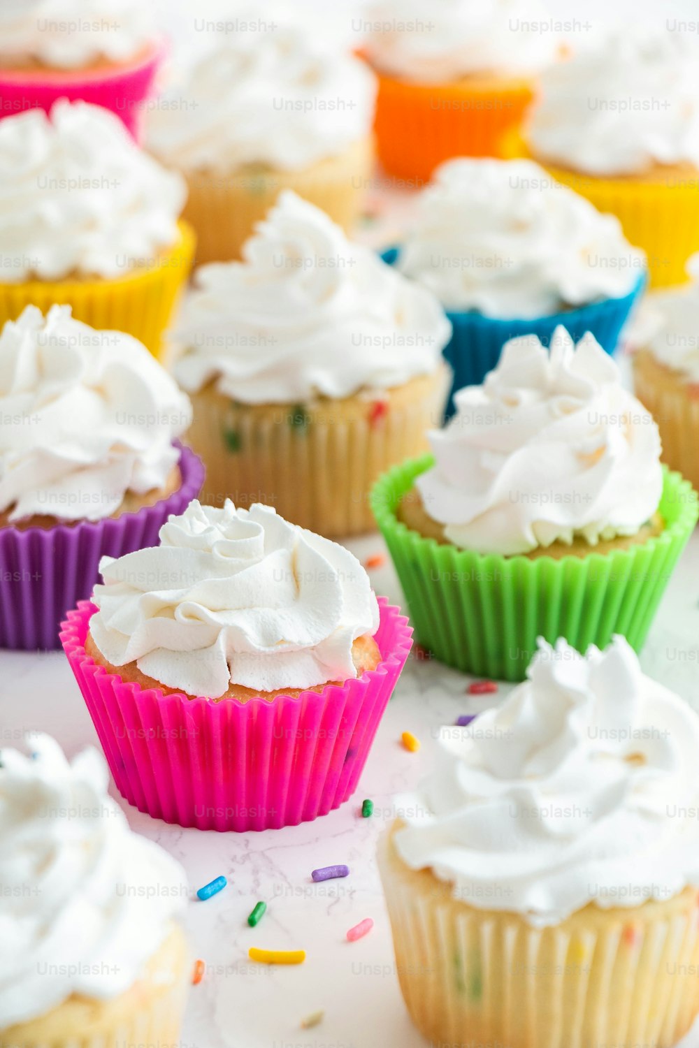 cupcakes with white frosting and sprinkles on a table