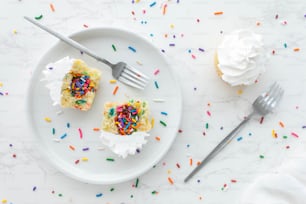 a white plate topped with cupcakes covered in sprinkles