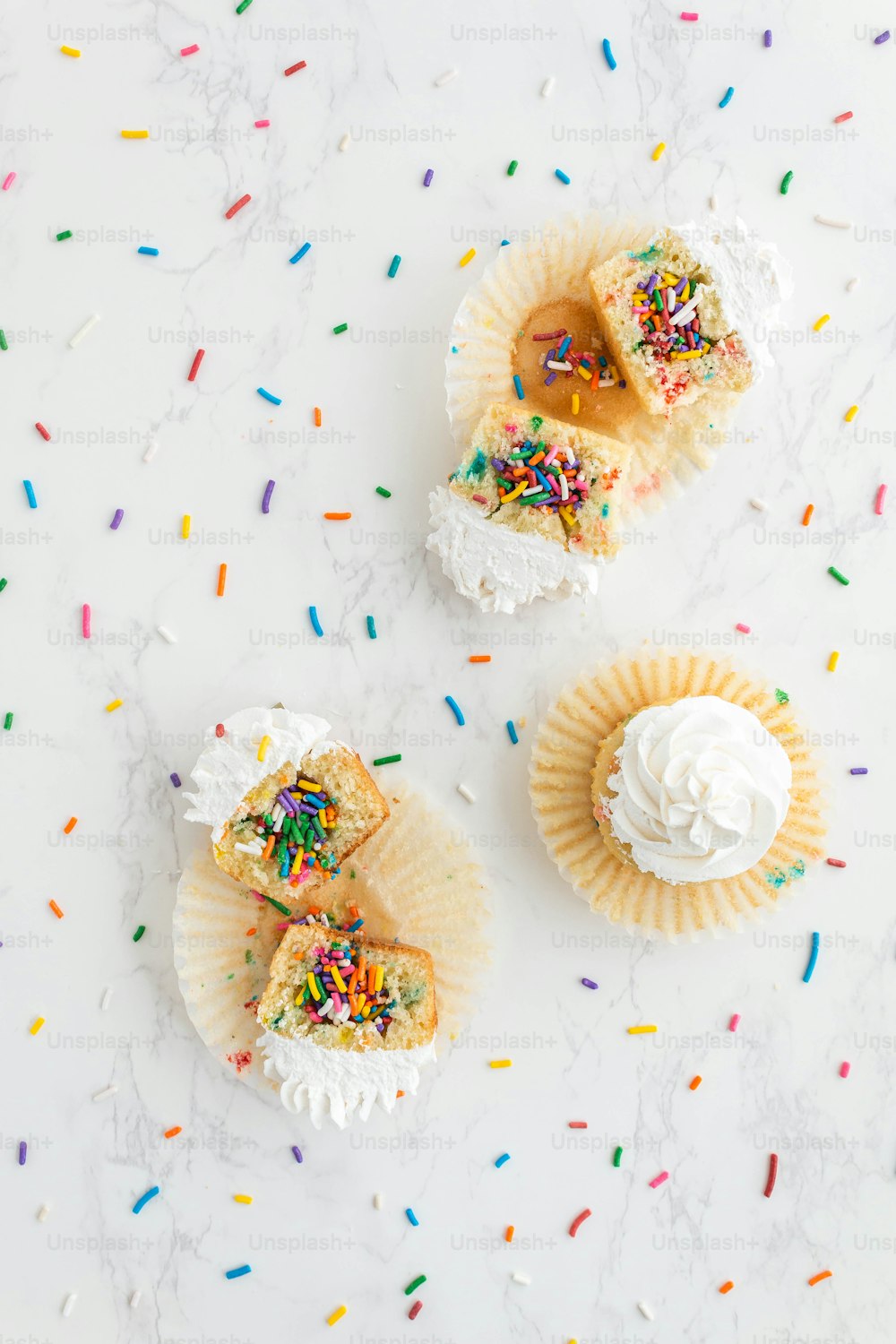 three cupcakes with white frosting and sprinkles