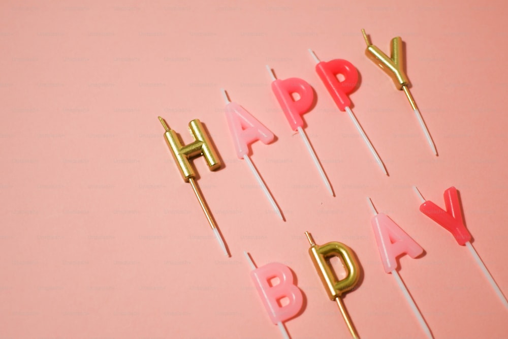 a pink and gold happy birthday cake on a stick