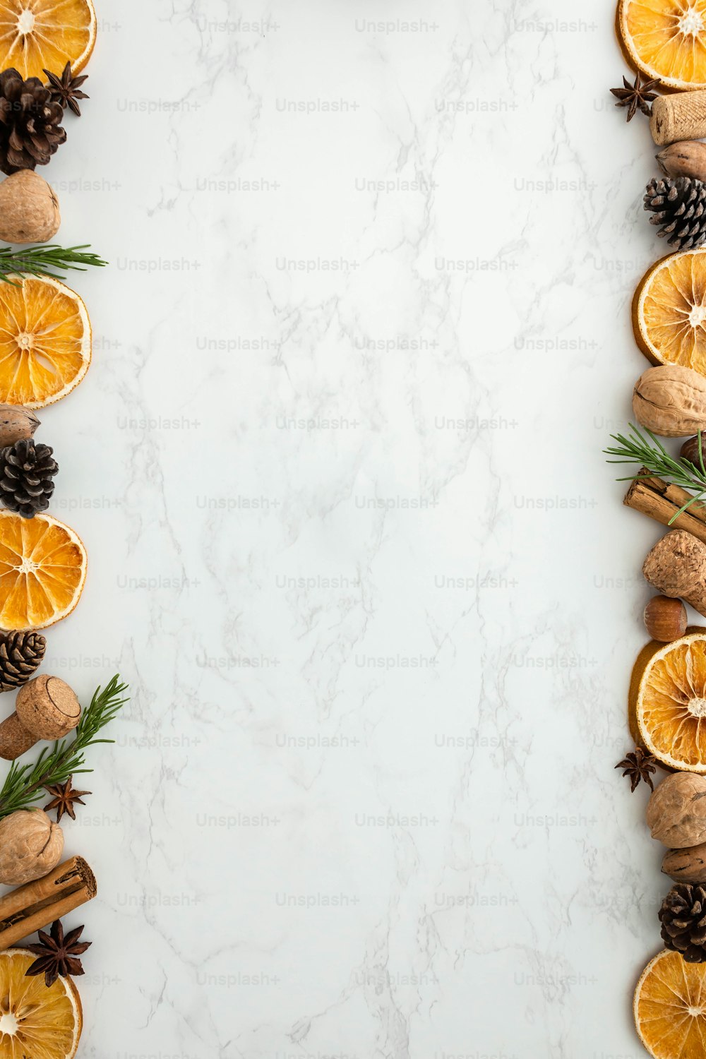 un fond de marbre blanc avec des tranches d’orange et des pommes de pin