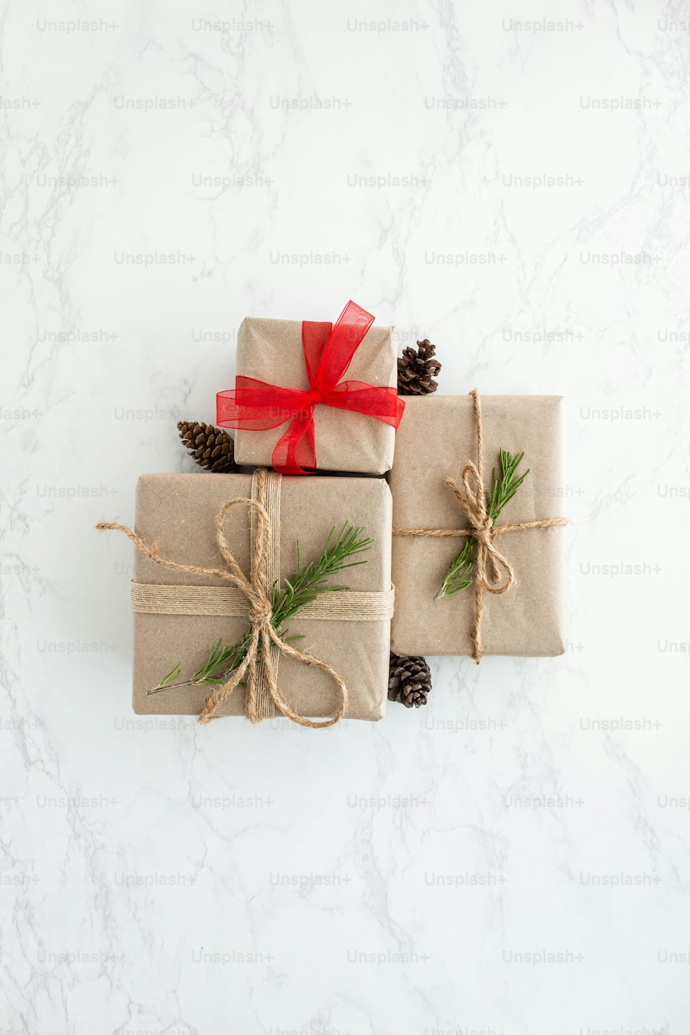 three wrapped presents tied with twine and pine cones