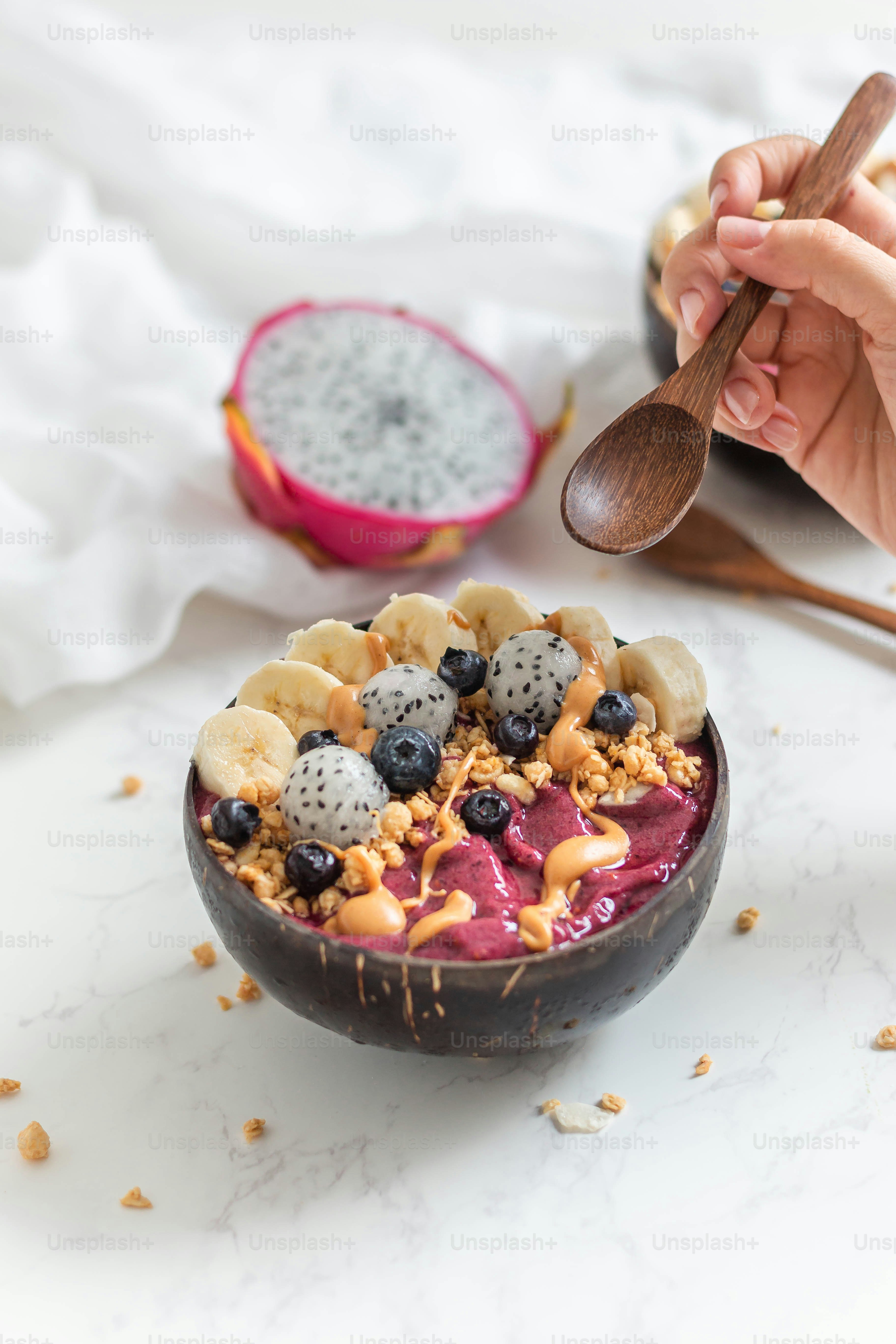 a person holding a spoon over a bowl of fruit