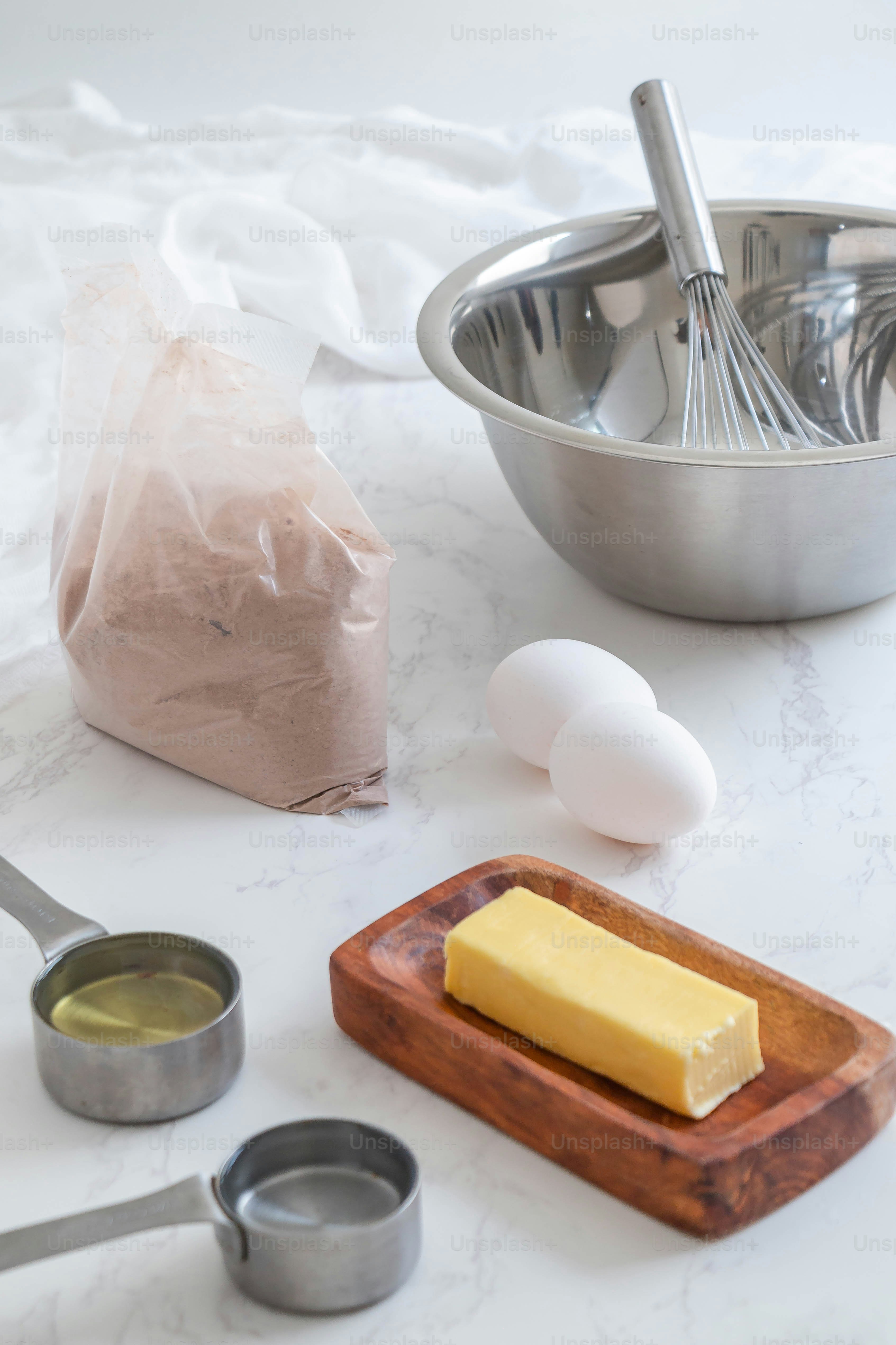 a table topped with a metal bowl filled with butter and other ingredients