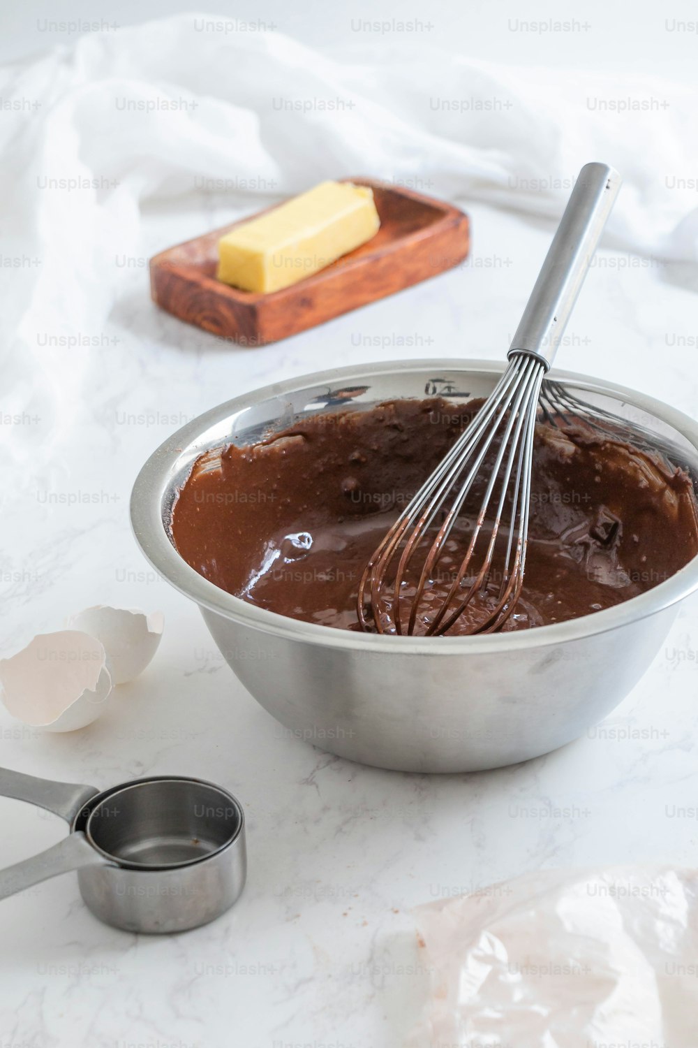 a metal bowl filled with chocolate and a whisk