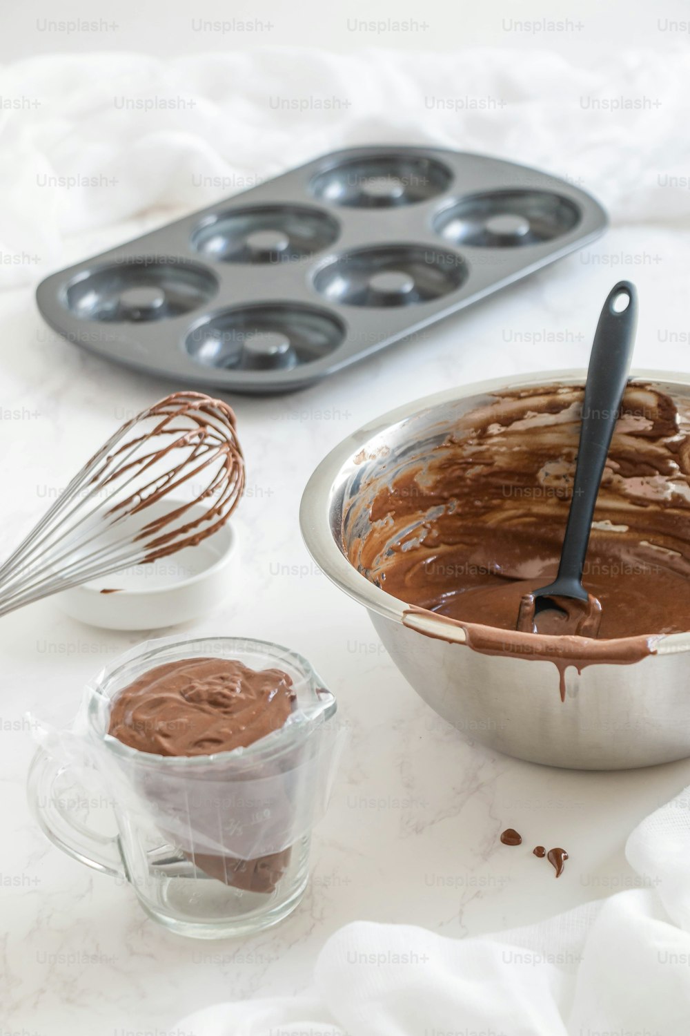 a pan filled with chocolate next to a muffin tin