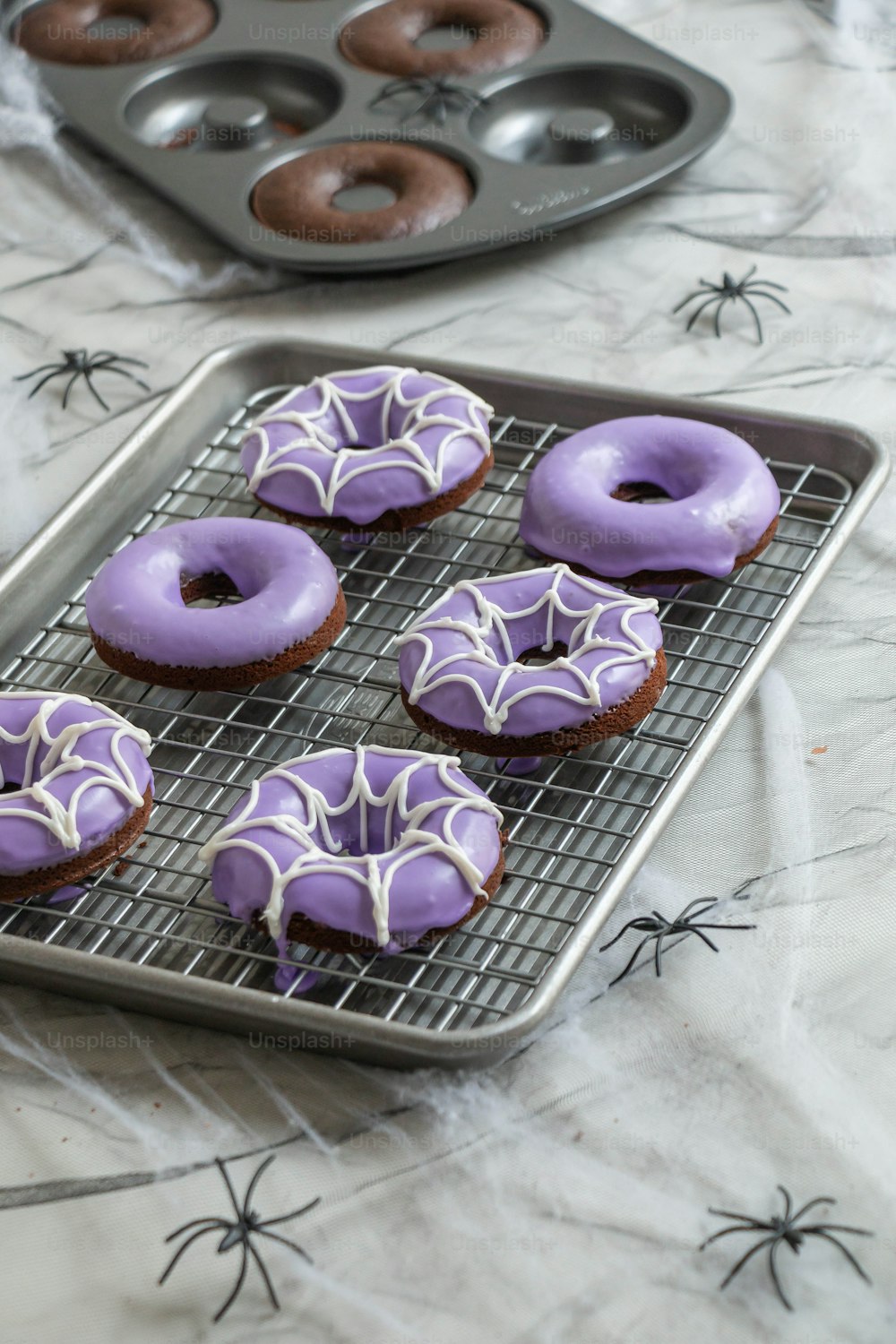 a tray of purple frosted donuts on a table