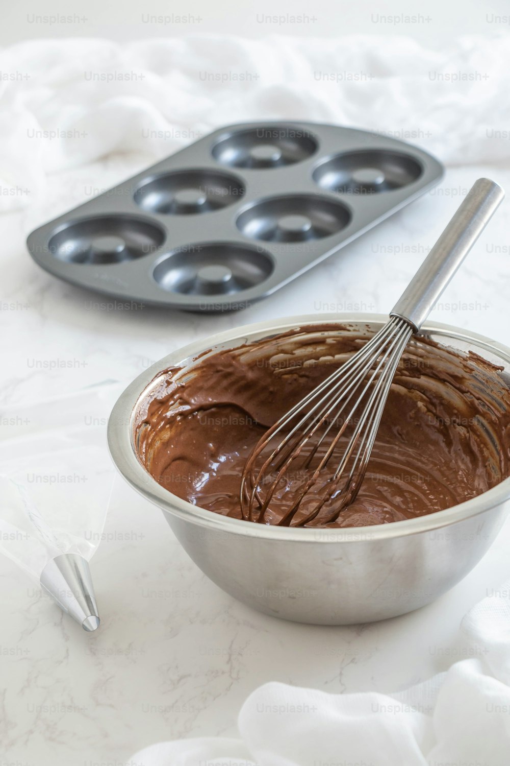 a metal bowl filled with batter next to a muffin pan