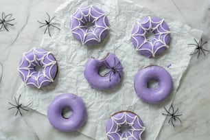 a table topped with purple frosted donuts covered in icing