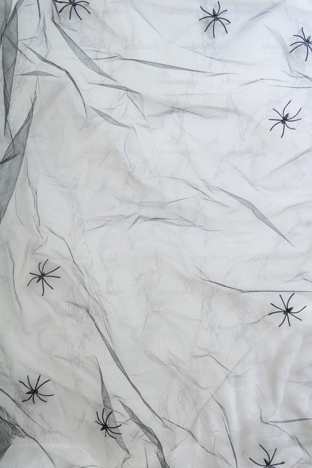 una sábana blanca con telas de araña negras