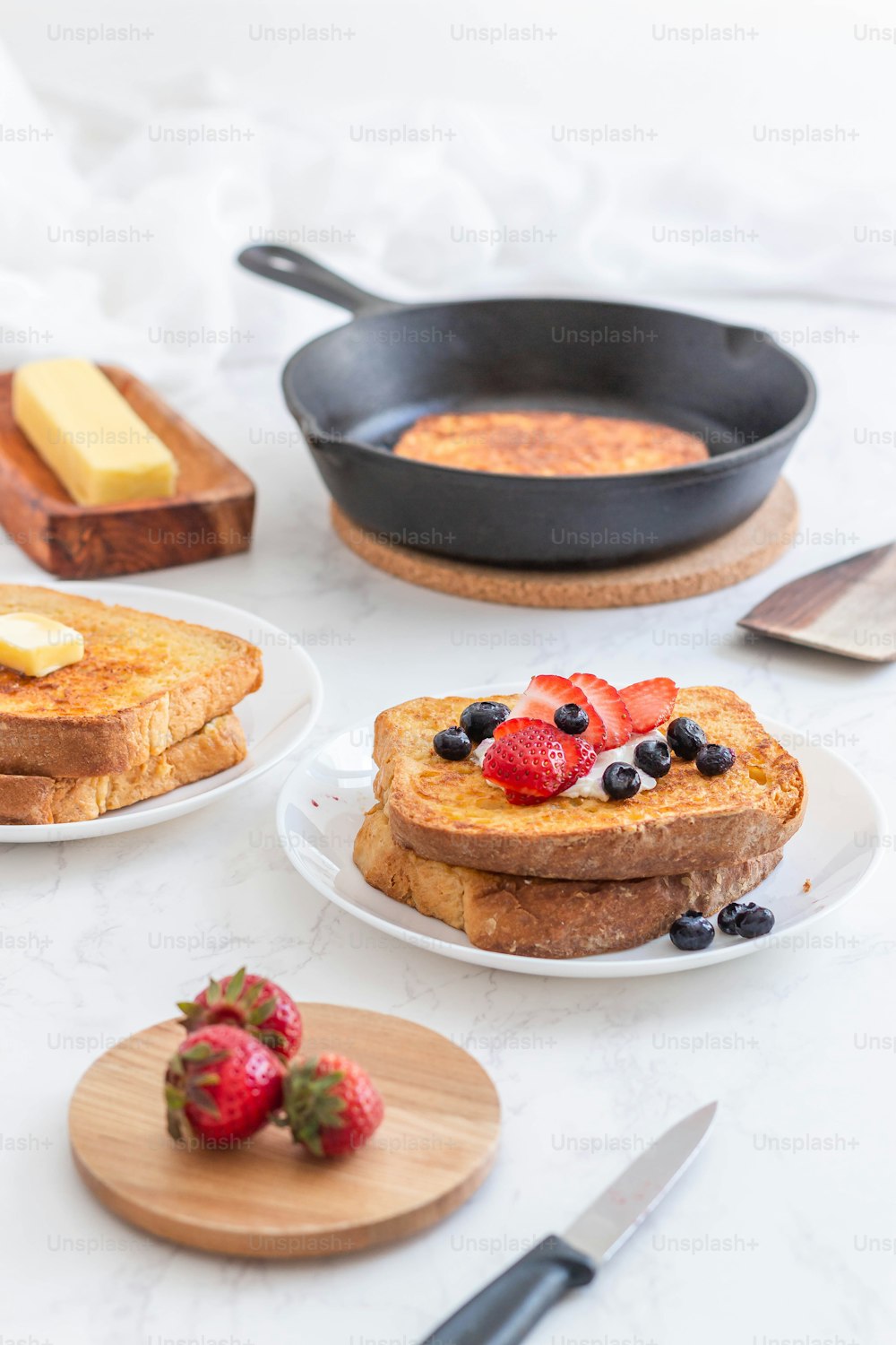 a table topped with plates of french toast and fruit