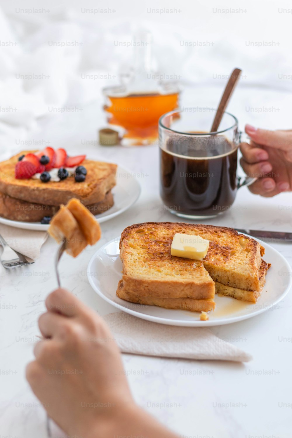 a person holding a spoon over a plate of french toast