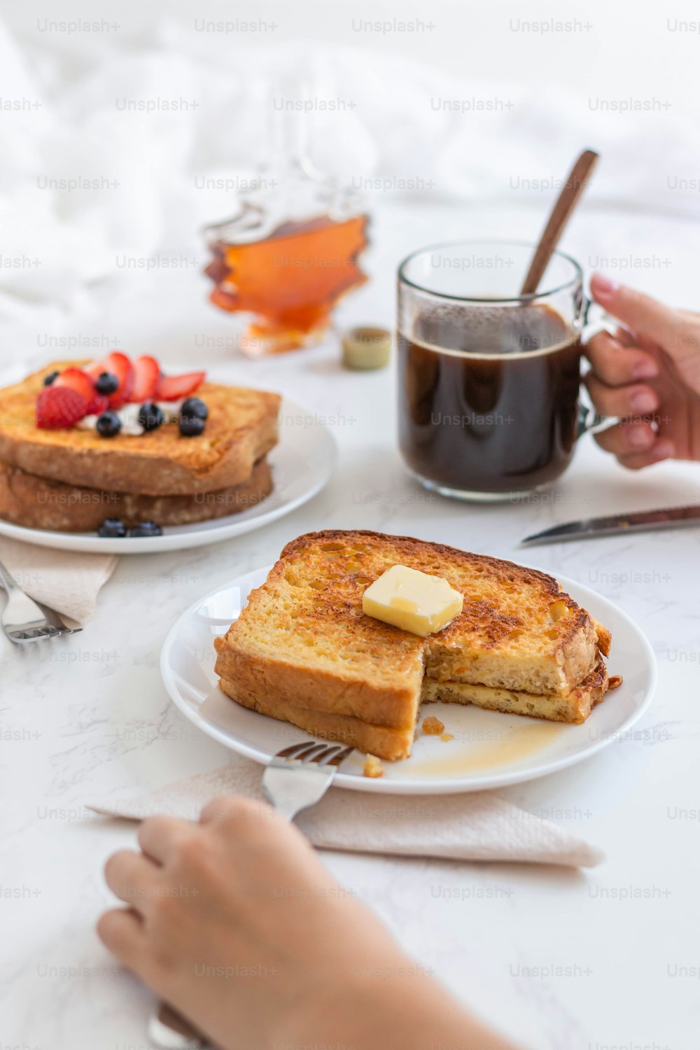 a table with two plates of french toast and a cup of coffee