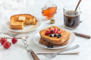 a table topped with plates of french toast and fruit